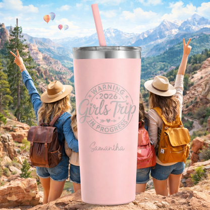 Pink tumbler with 'Warning: Girls Trip in Progress' text, surrounded by people on a mountain with balloons in the background.
